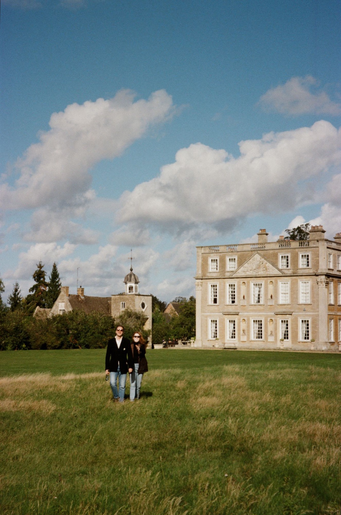 Two guests walking across the lawn in front of Hinwick House